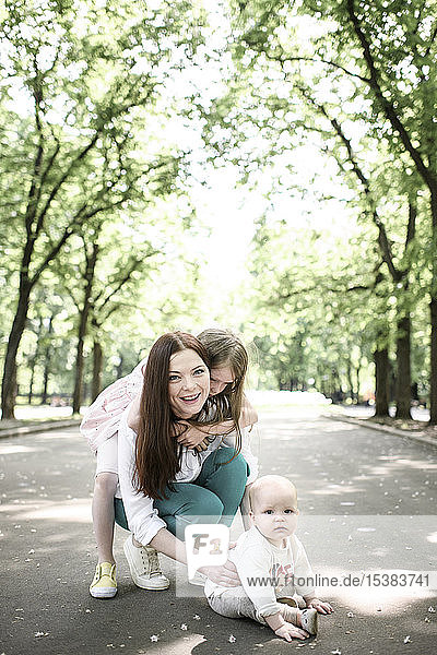 Lächelnde Mutter mit ihren beiden Kindern im Park