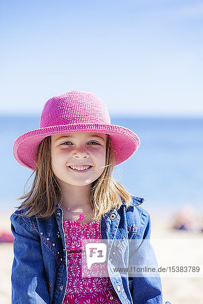 Porträt eines modischen kleinen Mädchens mit rosa Hut am Strand