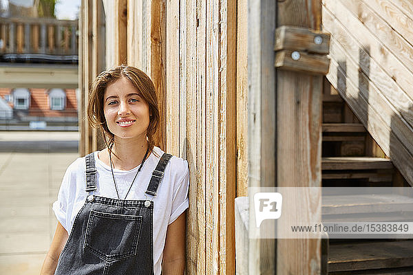 Portrait of smiling young woman leaning agianst wooden fence