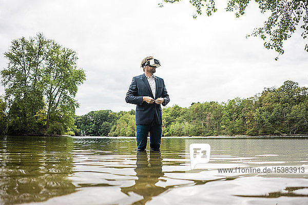 Geschäftsmann  der mit einer VR-Brille in einem See steht