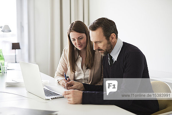 Geschäftsmann und Angestellter mit Laptop und Dokumenten  die am Schreibtisch im Büro arbeiten
