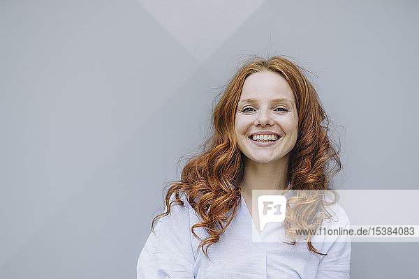 Porträt einer glücklichen rothaarigen Frau an einer Wand