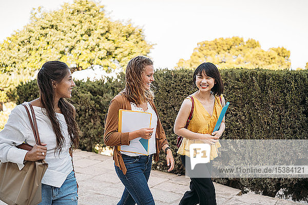 Three happy female friends walking around in a park