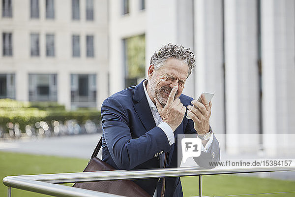 Happy mature businessman with smartphone in the city