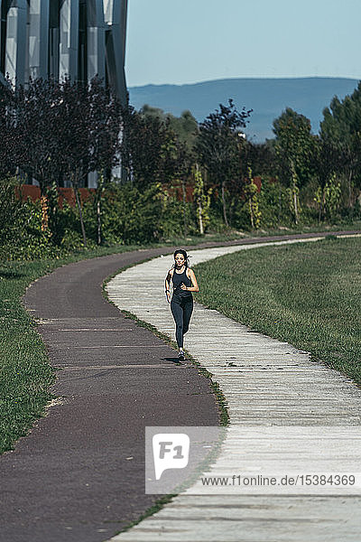 Junge Frau joggt in einem Park auf einem rot-weißen Weg