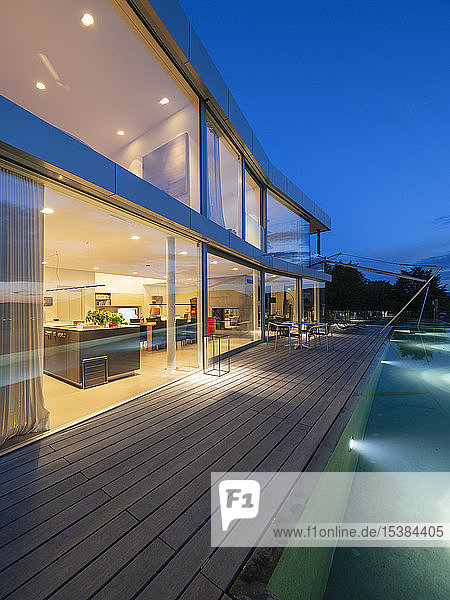 Schweiz  beleuchtete moderne Villa in der Dämmerung mit Terrasse und Pool im Vordergrund