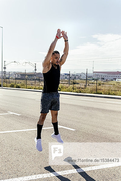 Sporty young man jumping on a road