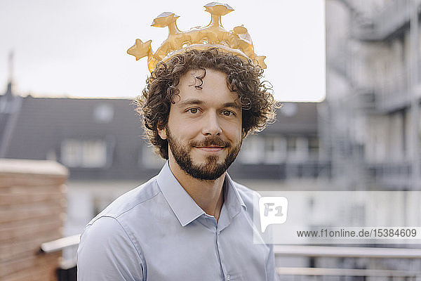 Porträt eines selbstbewussten Geschäftsmannes auf der Dachterrasse  der eine Krone trägt