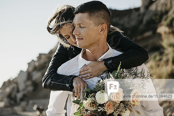 Affectionate bride embracing groom at the coast