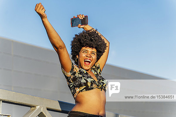 Lächelnde afro-amerikanische Frau mit rotem Smartphone