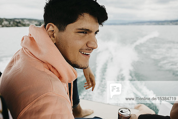 Happy young man having a drink on a boat trip on a lake