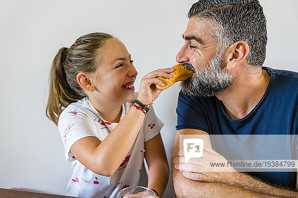 Glückliche Tochter füttert Vater zu Hause