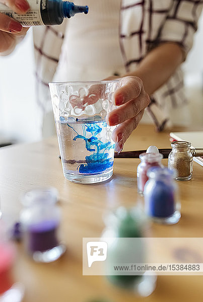 Maler der flüssige Farbe in ein Glas Wasser füllt Teilansicht