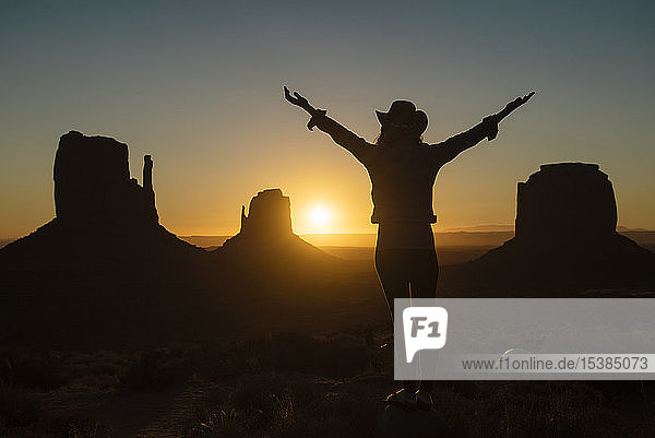 USA  Utah  Monument Valley  Silhouette einer glücklichen Frau mit Cowboyhut  die den Sonnenaufgang genießt