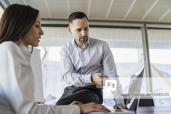 Businessman and businesswoman with laptop working in office