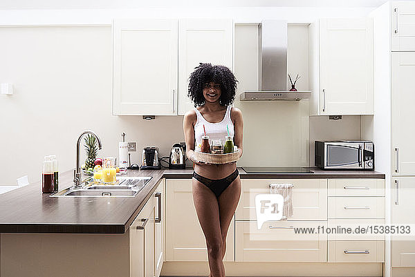 Lächelnde junge Frau trägt gesundes Frühstückstablett in der Küche