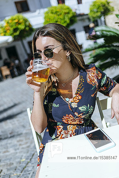 Spanien  Cádiz  Vejer de la Frontera  junge Frau sitzt im Straßencafé und trinkt ein Glas Bier