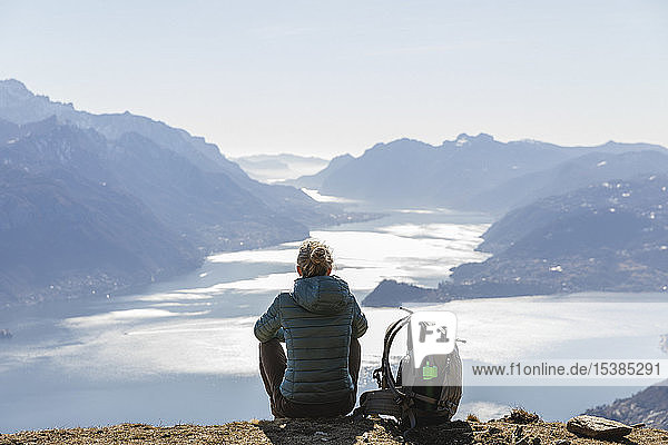 Italien  Como  Lecco  Frau auf einer Wanderung in den Bergen über dem Comer See sitzend und geniesst die Aussicht
