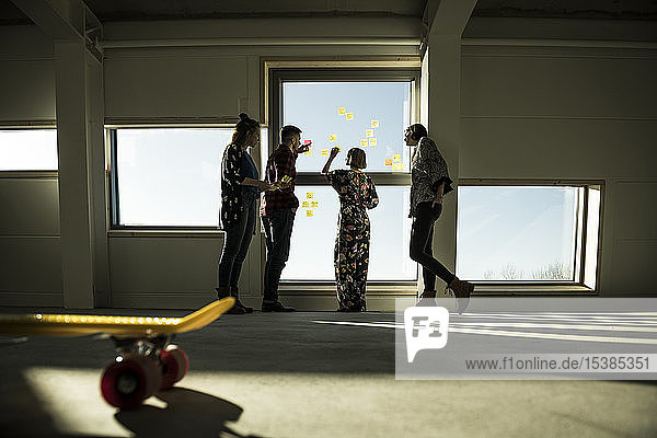 Creative professinal standing in office brainstorming putting sticky notes on a window