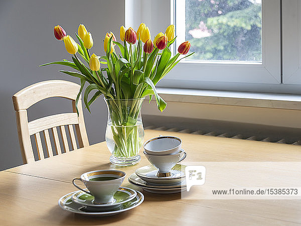 Bouquet of red and yellow tulips on dining table with coffee cups
