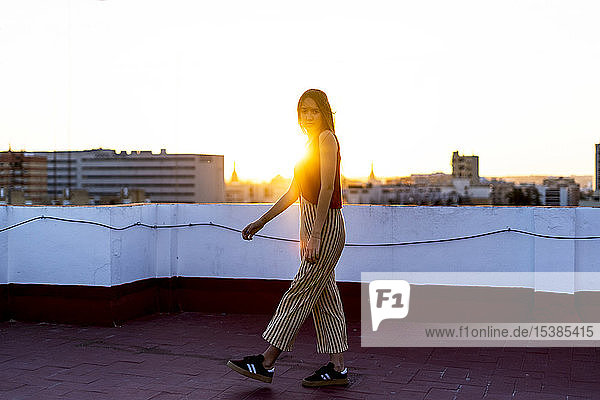 Teenager-Mädchen geht bei Sonnenuntergang auf einer Dachterrasse in der Stadt