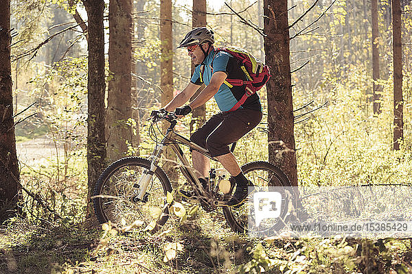 Mann fährt Mountainbike auf Waldweg