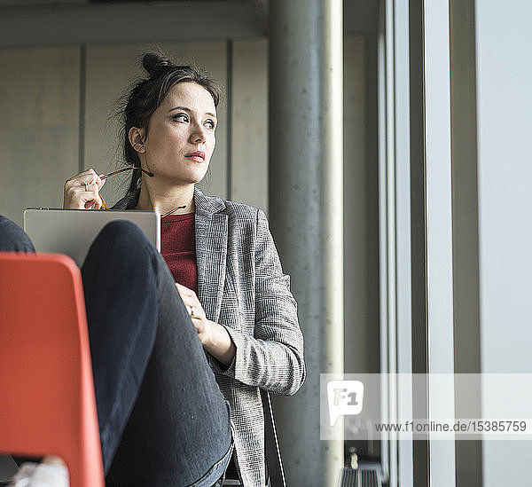 Businesswoman sitting on chair in office with laptop looking sidways