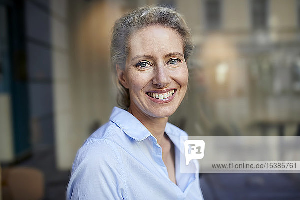 Porträt einer lächelnden Frau hinter einer Fensterscheibe