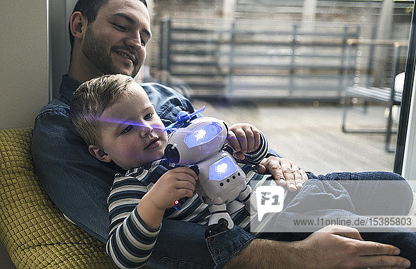 Father and son playing with a toy robot at home