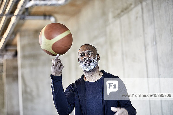 Porträt eines reifen Geschäftsmannes mit Basketball im modernen Büro