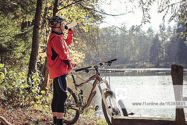 Mann mit Mountainbike bei einer Pause an einem See im Wald