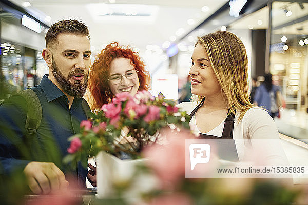 Verkäuferin berät Ehepaar im Blumenladen