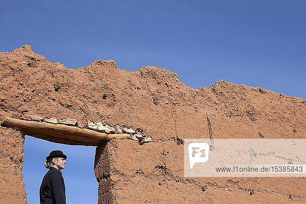 Morocco  Ait-Ben-Haddou  man wearing a bowler hat under loam wall