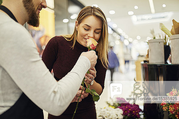 Florist lässt Kunden im Blumenladen an der Blume riechen