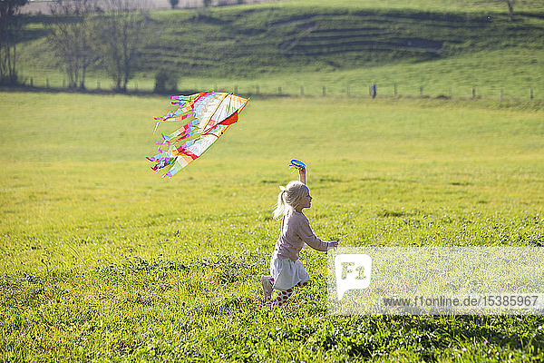 Kleines Mädchen rennt im Feld mit Drachen