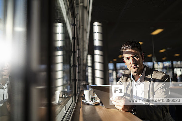 Porträt eines Geschäftsmannes mit Tablette am Fenster in einem Café
