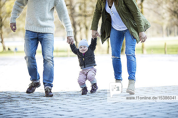 Portrait of happy girl walking hand in hand with parents