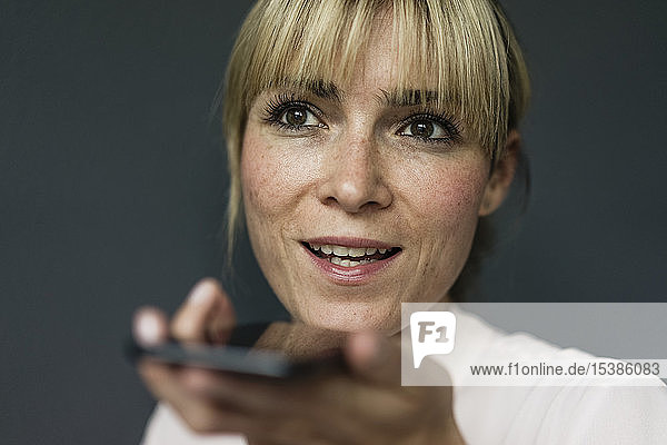 Porträt einer blonden Geschäftsfrau  die ein Smartphone benutzt