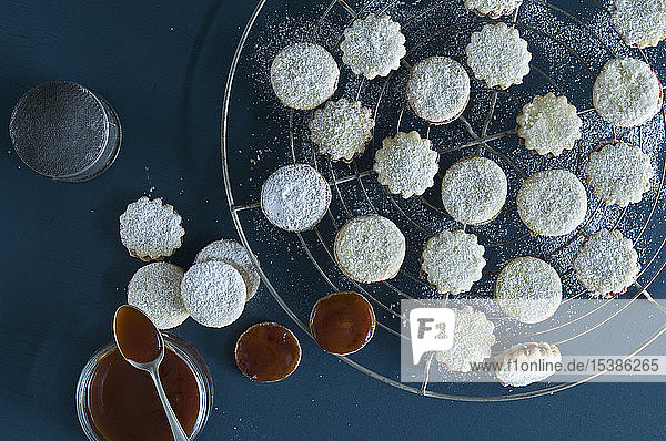 Weihnachtsplätzchen Spitzbuben auf einem Backrost  Marmelade im Glas  Hagebuttenkonfitüre  Puderzucker