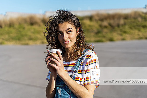 Junge Frau trinkt Kaffee aus einer Wegwerftasse