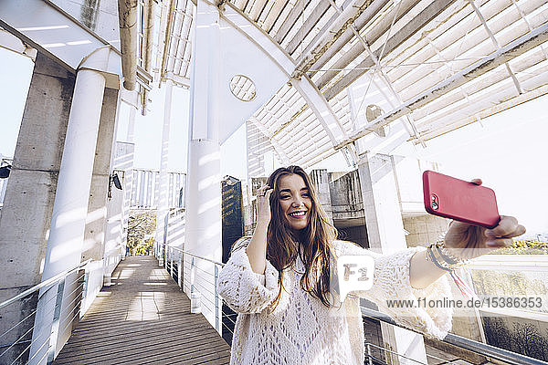 Happy young woman taking a selfie on a bridge