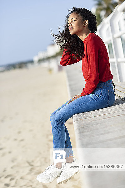 Junge Frau sitzt an der Strandpromenade