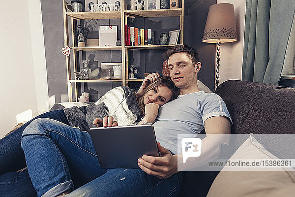 Young couple using tablet on couch at home