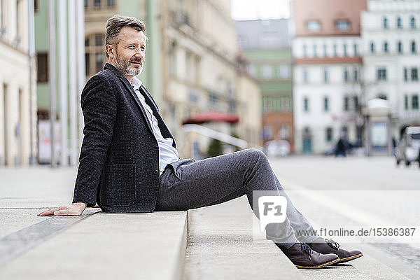 Deutschland  Zwickau  entspannter reifer Geschäftsmann sitzt auf Stufen im Freien