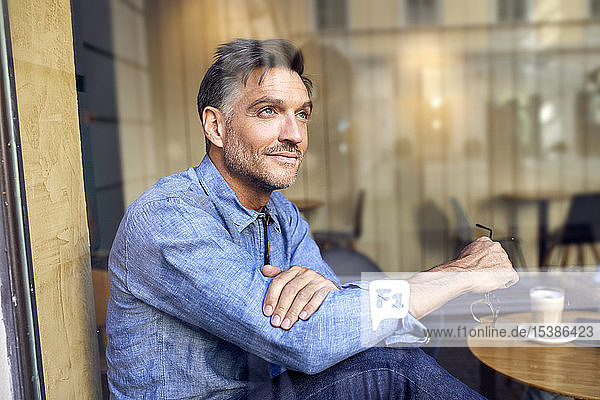 Porträt eines Mannes hinter einer Fensterscheibe in einem Cafe