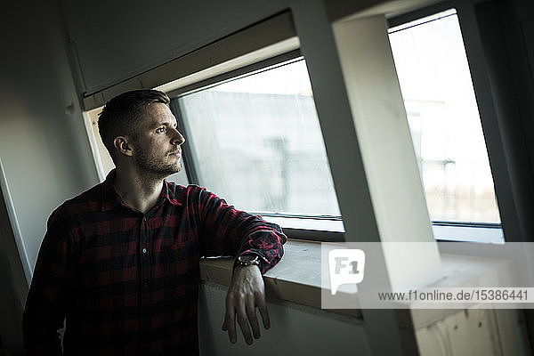 Young man looking out of window daydreaming