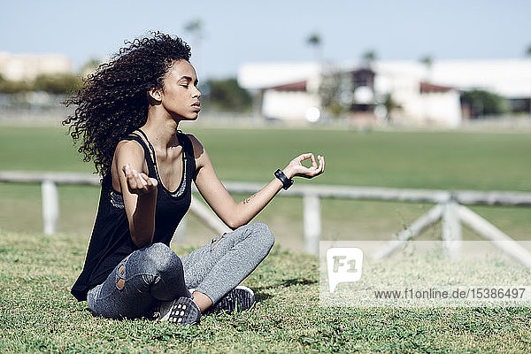 Sportliche junge Frau beim Yoga auf dem Rasen