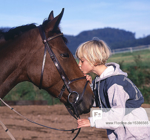 Mädchen  das ein Pferd liebevoll küsst