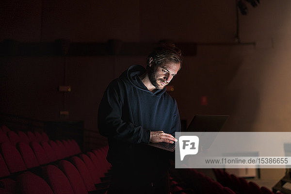Regisseur steht mit Laptop im Theatersaal