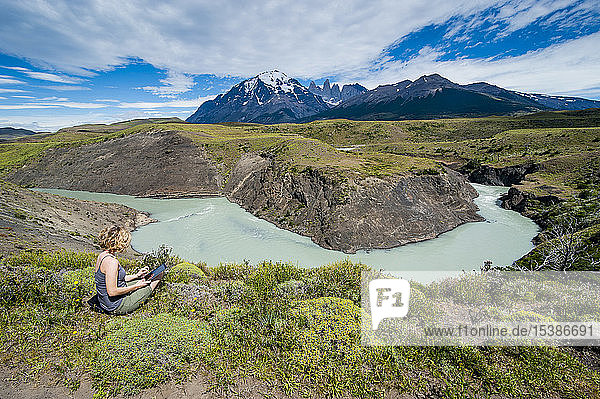 Chile  Patagonien  Frau mit Tablette an einer Flussbiegung im Torres del Paine Nationalpark